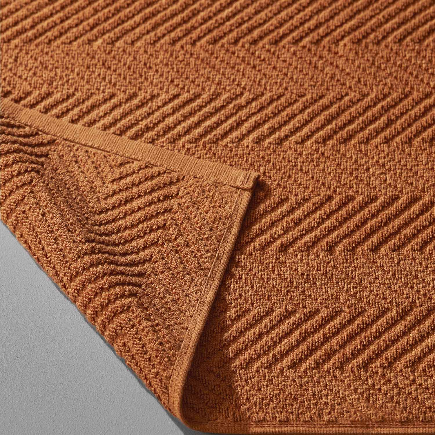 Close-up of a textured orange treatment towel, ideal for spa clay and mud treatments with a stylish chevron pattern.