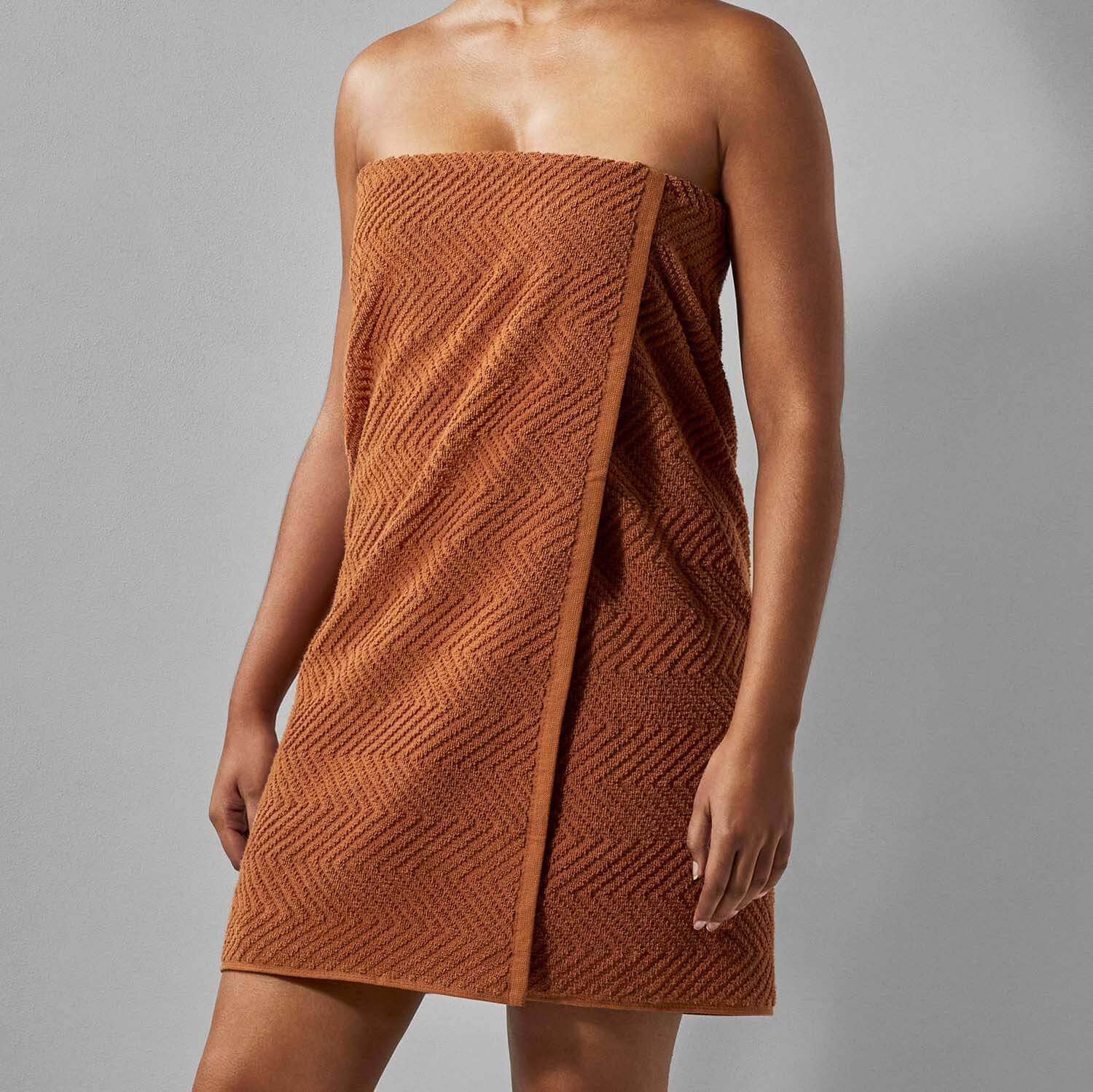 Model showcasing a clay treatment towel in warm brown, ideal for spa and wellness settings.