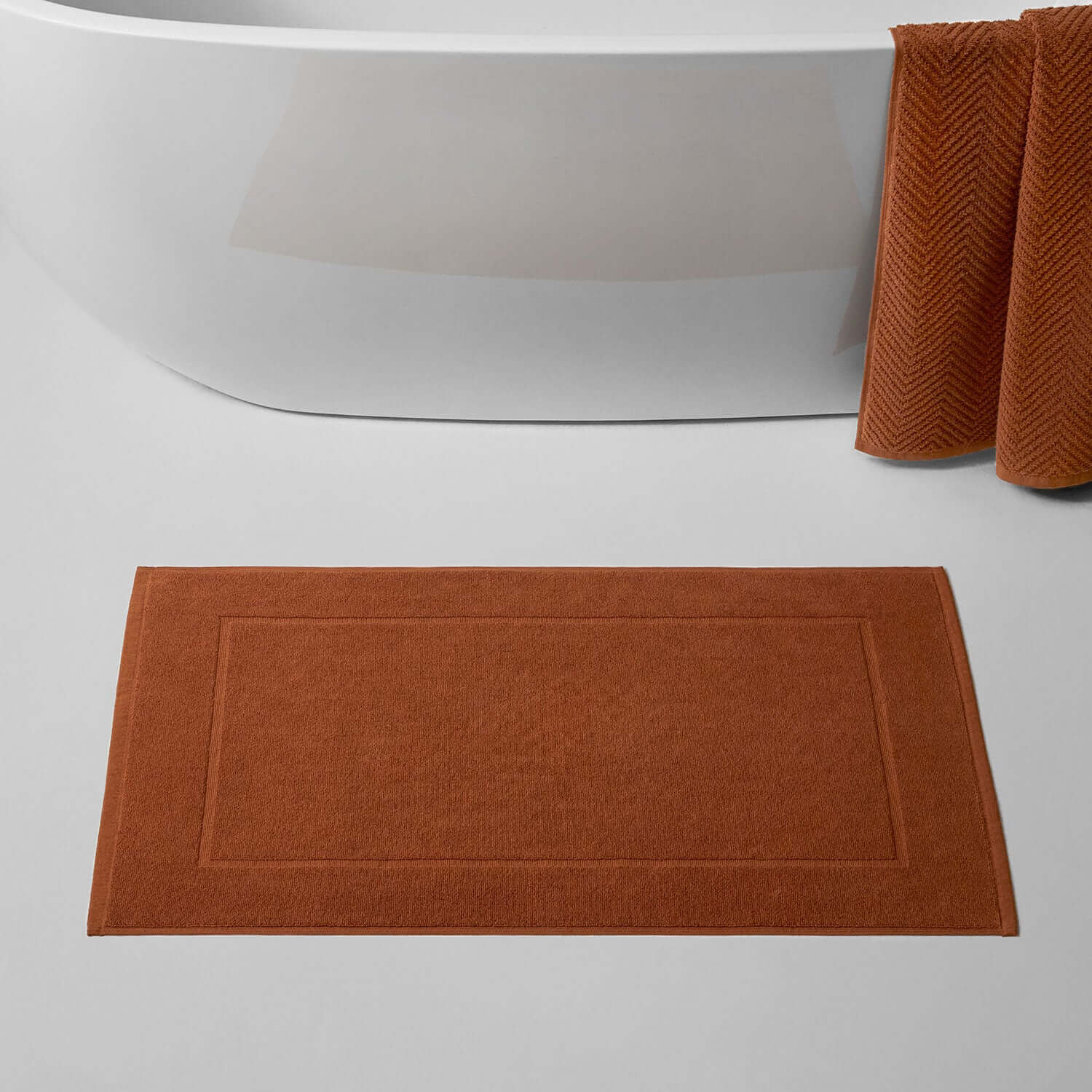 Clay treatment mat in rich brown color beside a modern bathtub, perfect for spa and home use.