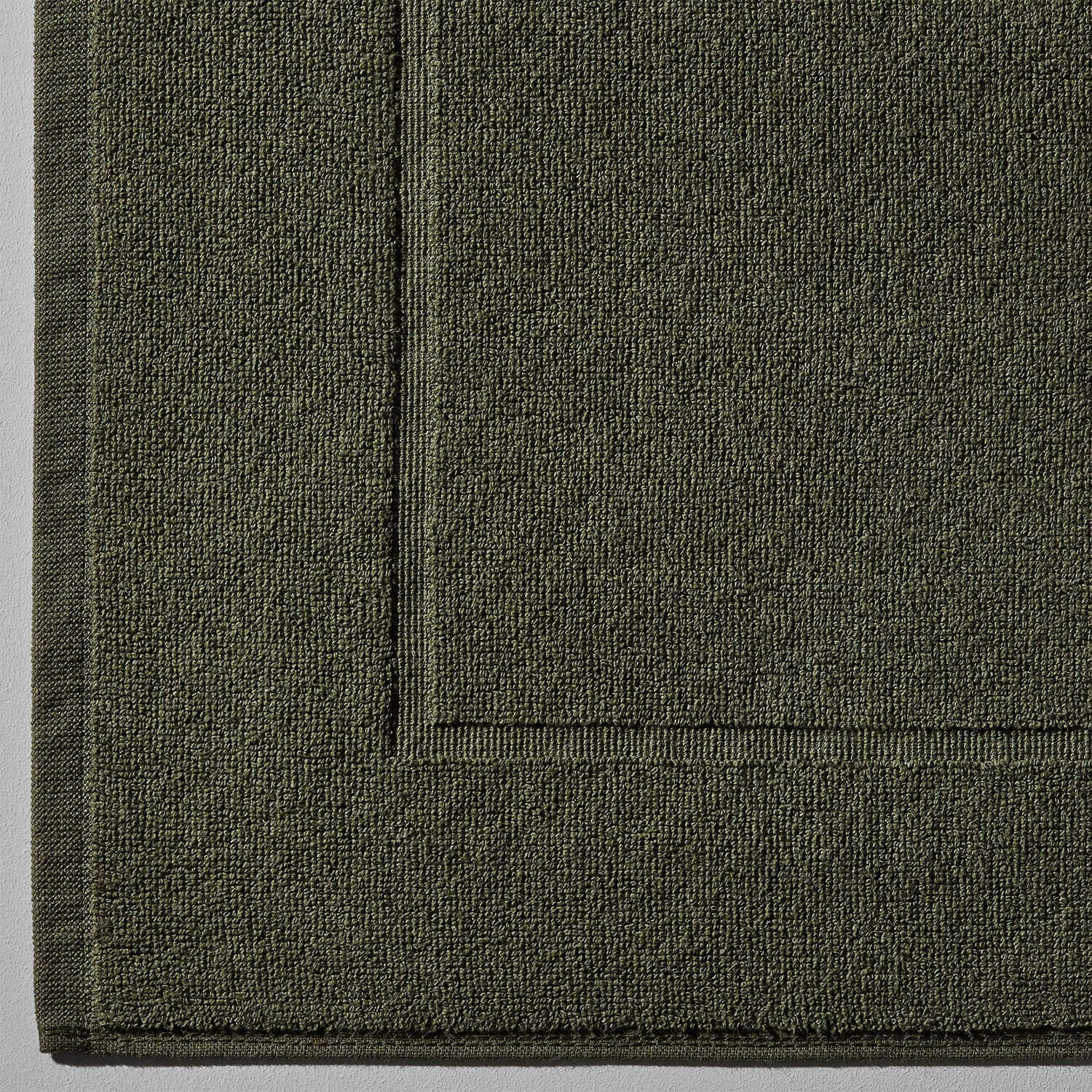 Close-up of olive green treatment mat, designed for mud and clay spa treatments, featuring a textured surface.