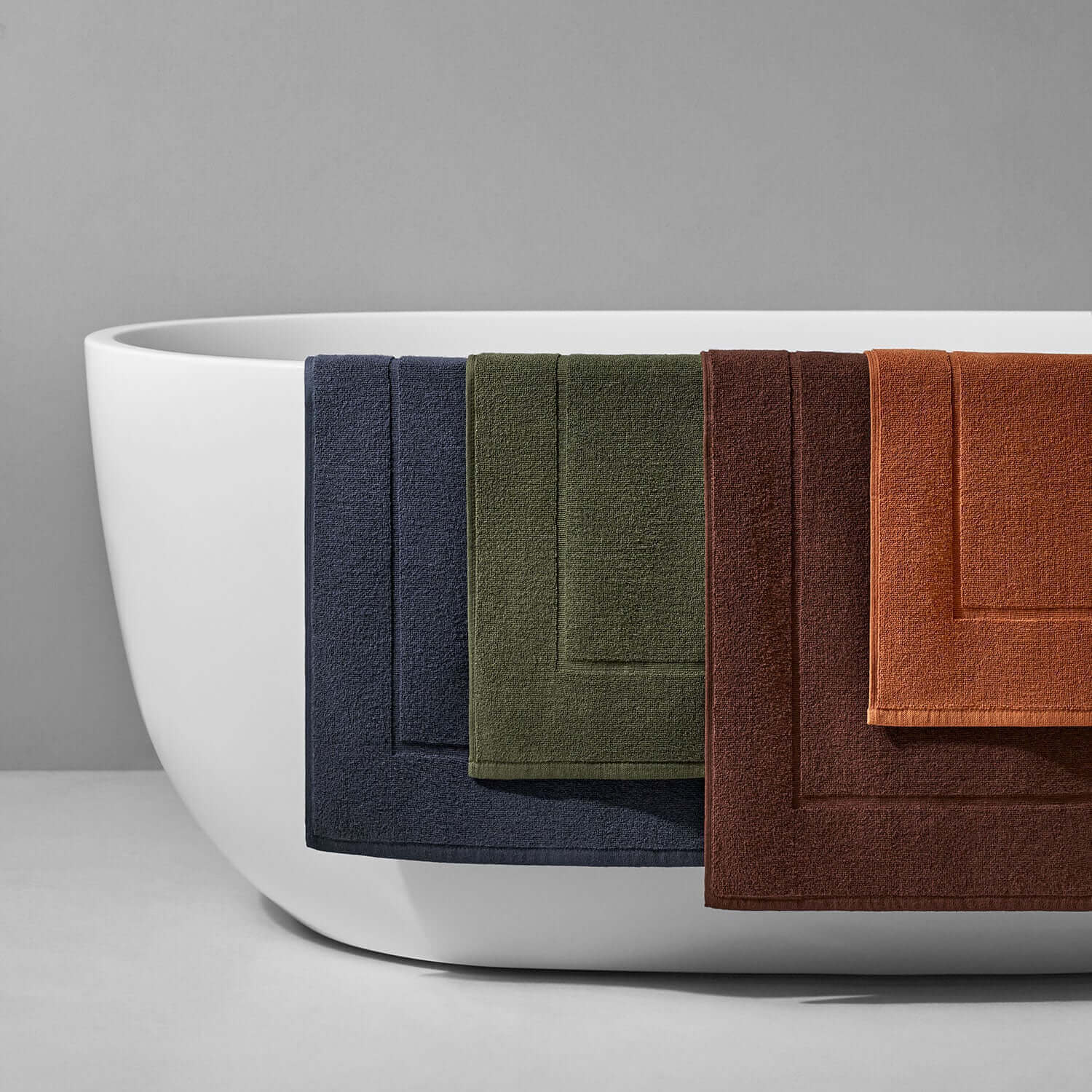 Treatment Mat Bruno in Olive, Slate, and Clay colors displayed against a modern bathtub, ideal for spa treatments.