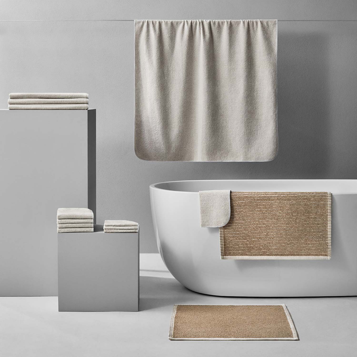 Tuxedo Bath Bundle in sand color, featuring eco-luxury towels and mats in a modern bathroom setting.