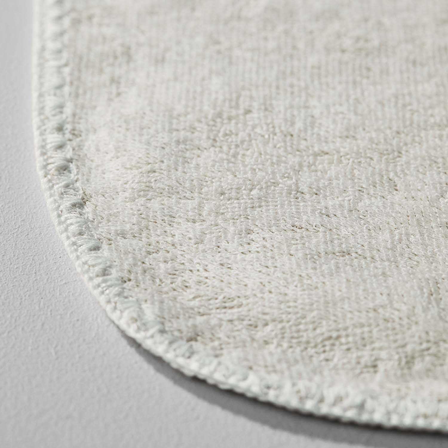 Close-up of a soft, textured light grey textile with rounded edges, showcasing its elegant and premium quality.