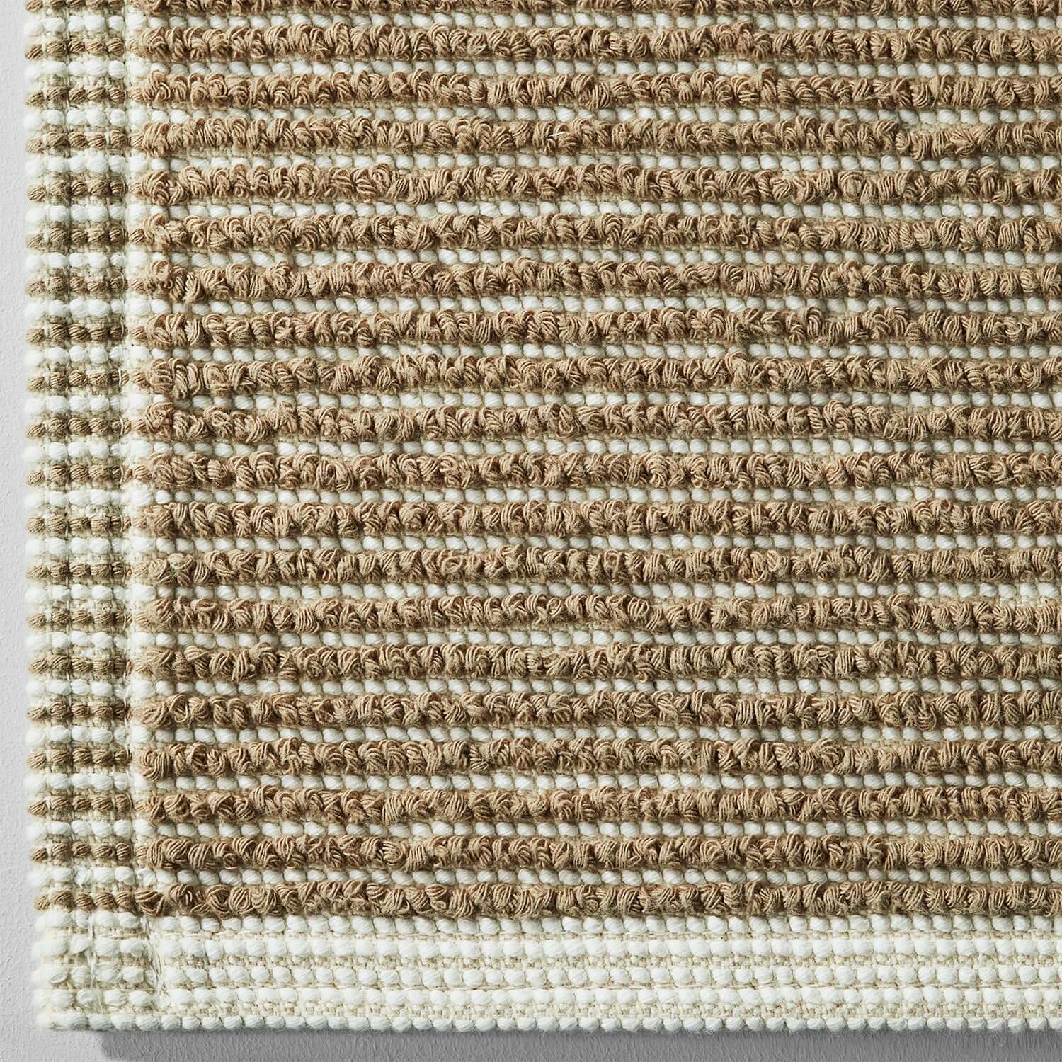 Close-up of Tuxedo Bath Bundle Sand rug, showcasing eco-friendly weave in neutral tones, perfect for modern bathroom decor.