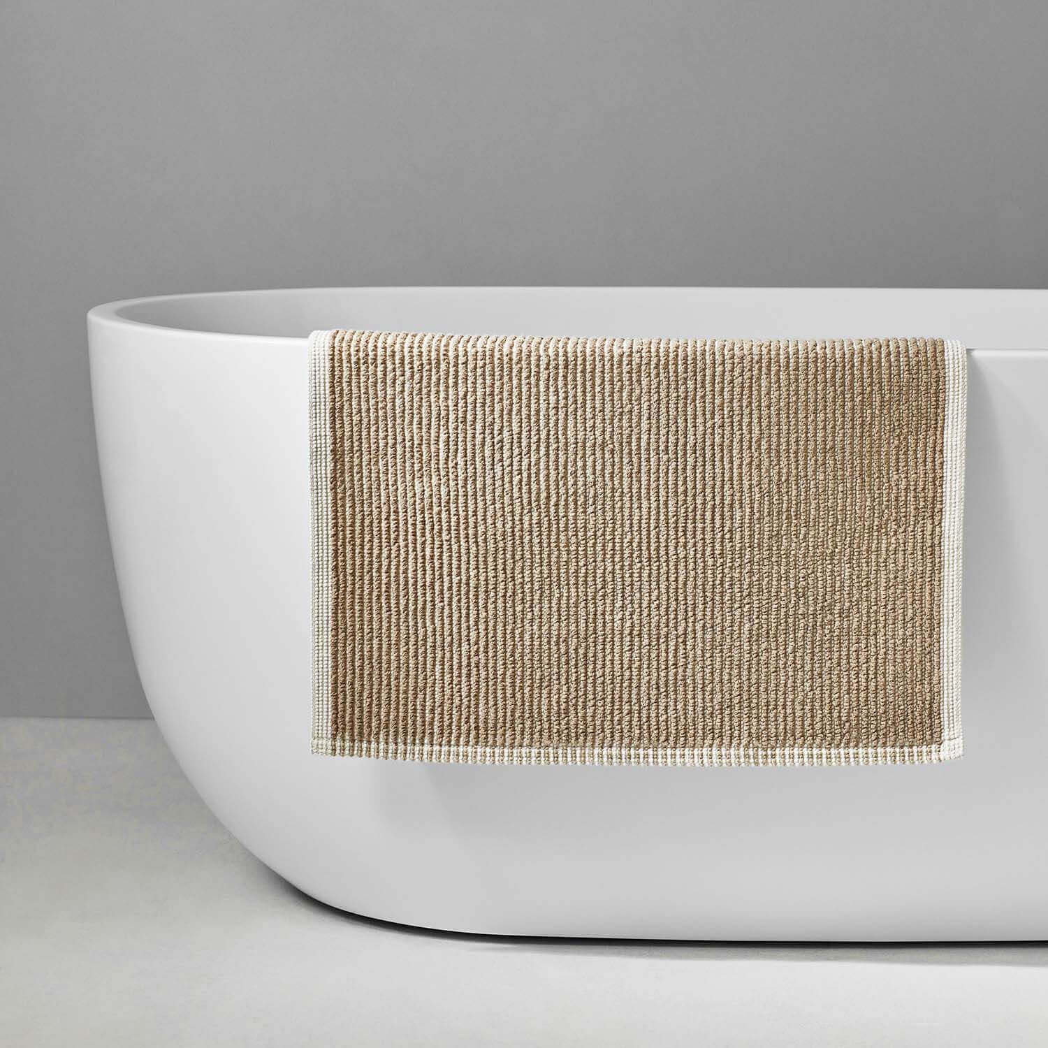 Tuxedo Mat Sand displayed on a modern white bathtub, showcasing its innovative shape and grey stripe design.