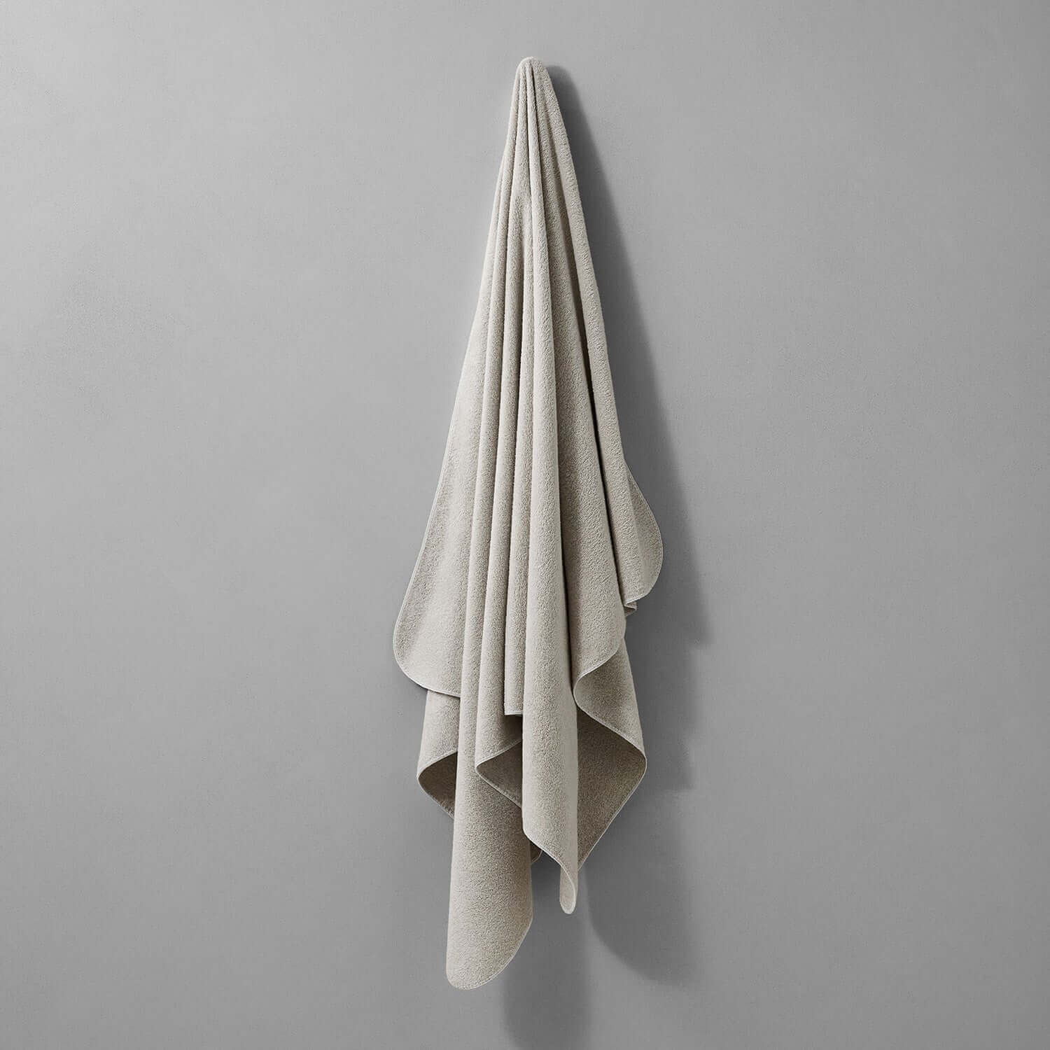Tuxedo Towel in Sand color, showcasing its soft, multi-tonal hues against a gray background.