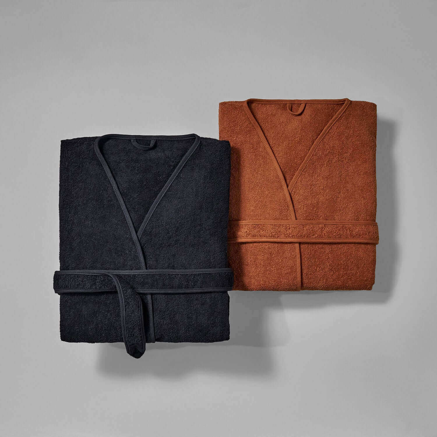 Wabi Sabi black and brown robes on grey background, showcasing minimalist design and timeless craftsmanship.