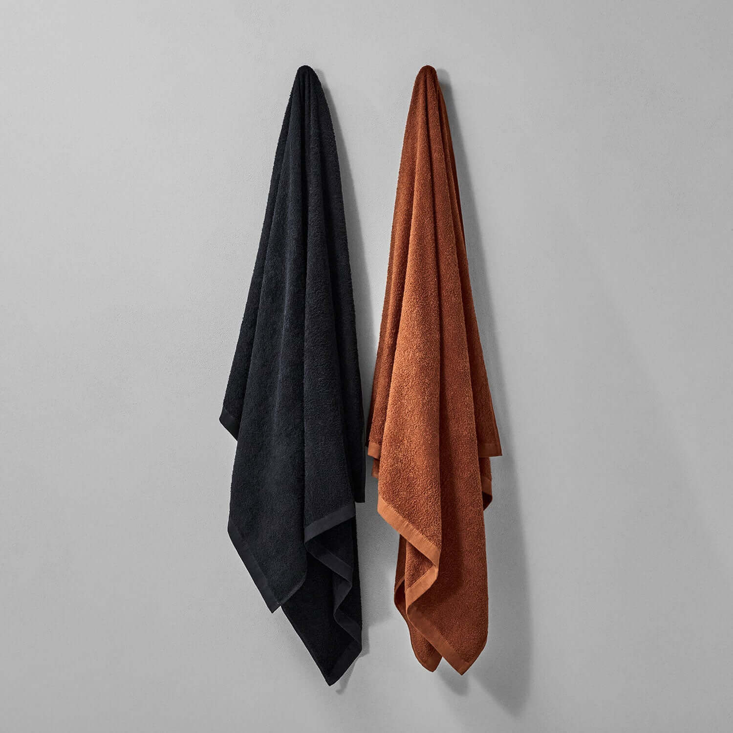 Wabi Sabi towels in black and rust hanging on a wall, showcasing minimalist design and timeless craftsmanship.