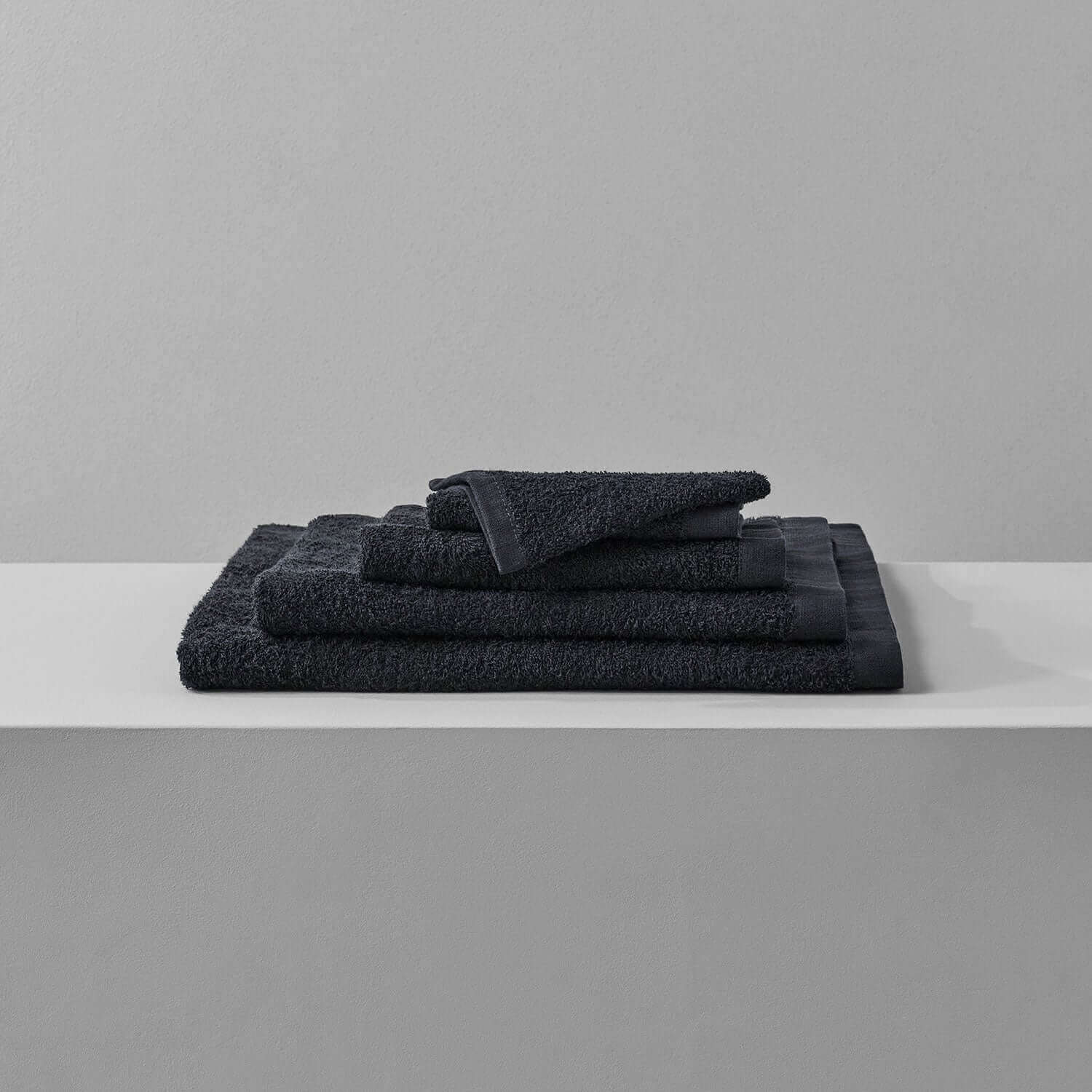 Wabi Sabi black towels stacked on a shelf, showcasing minimalist design and luxurious texture.