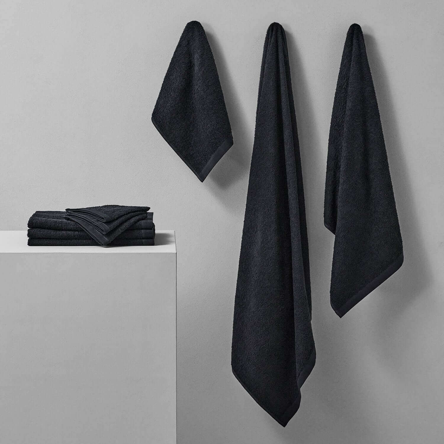 Wabi Sabi black towels hanging and stacked, showcasing minimalist design and sustainable luxury.