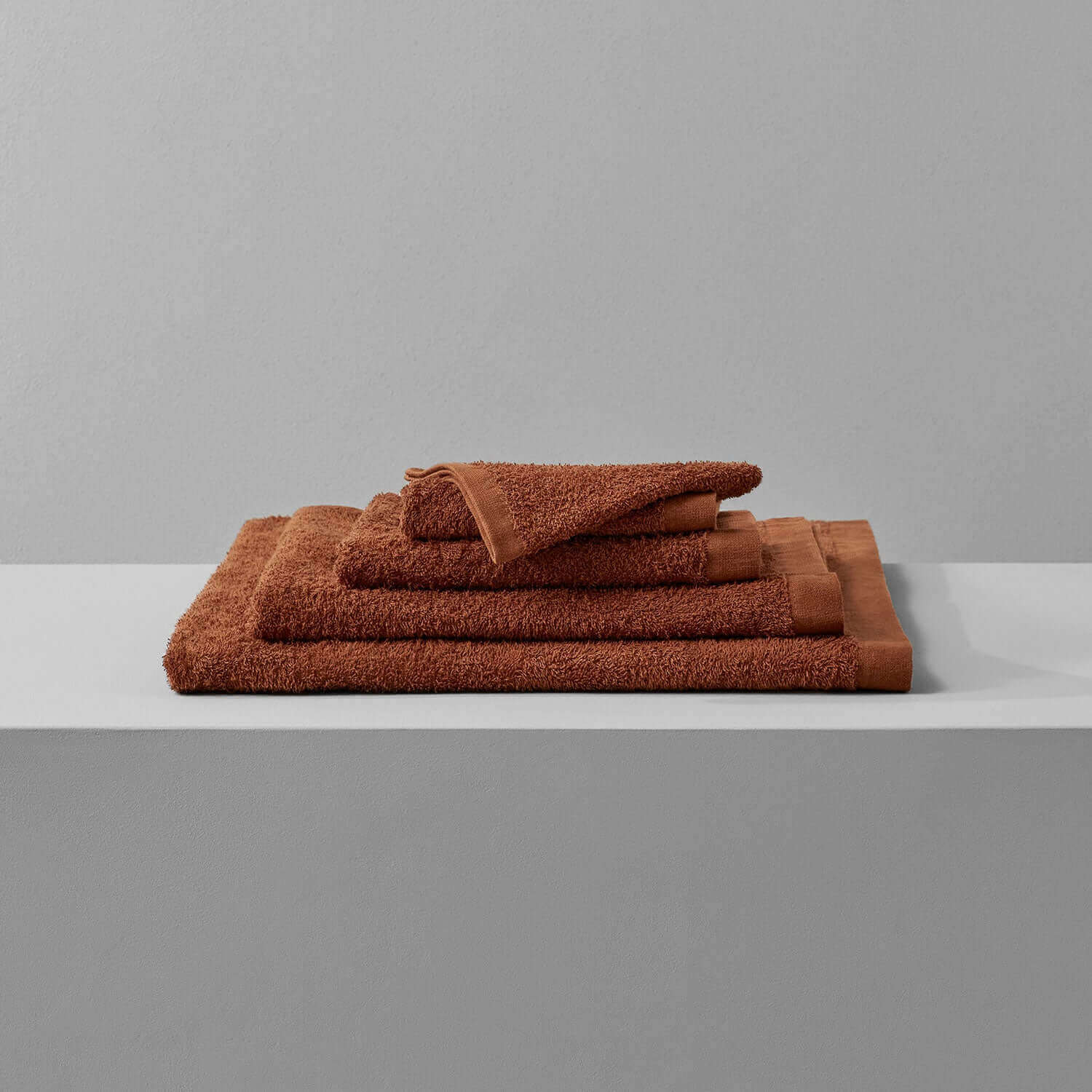 Wabi Sabi copper towels stacked on a minimalistic shelf, highlighting sustainable luxury and timeless craftsmanship.