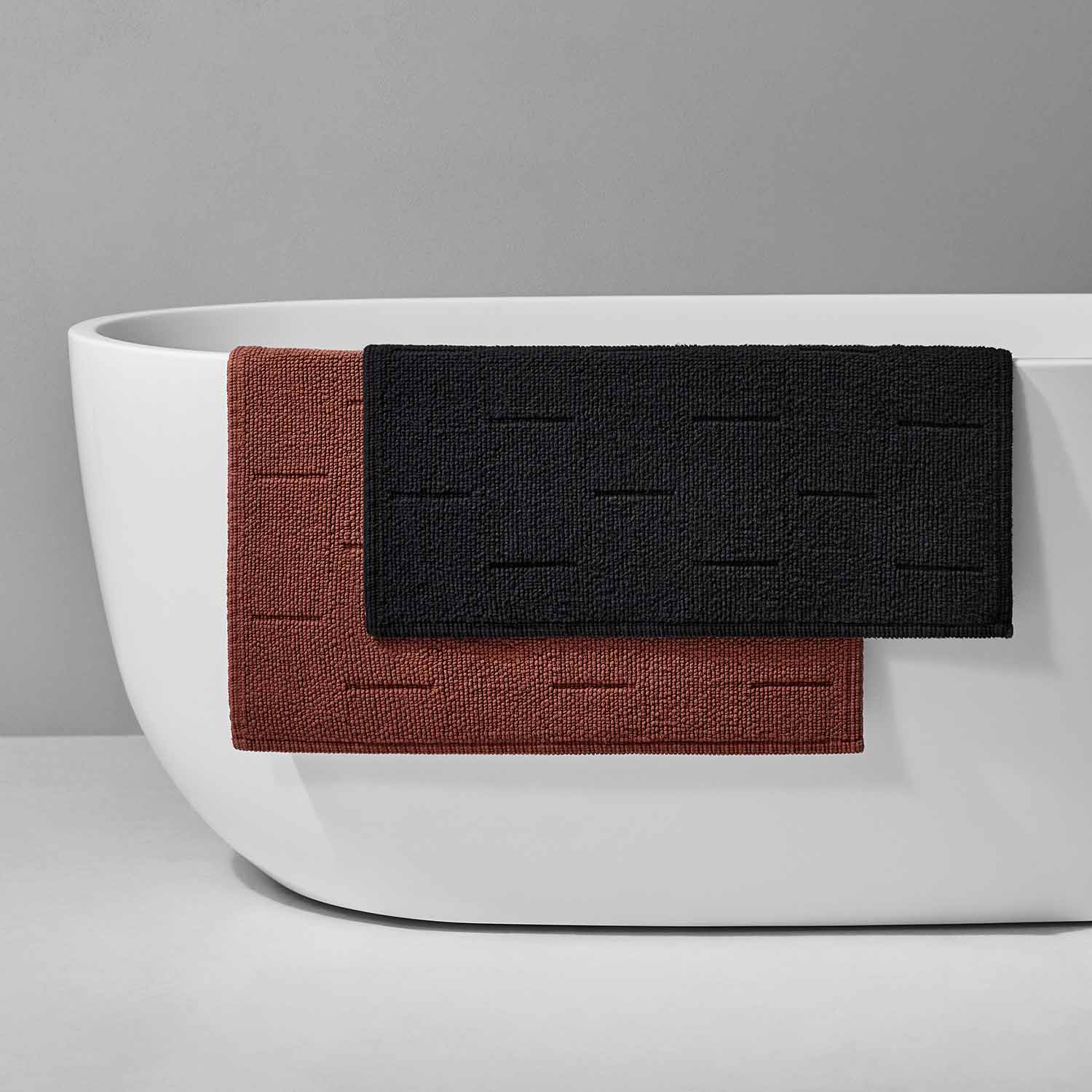 Wabi Sabi tub mats in copper and black, showcasing minimalist Japanese design by the bathtub.