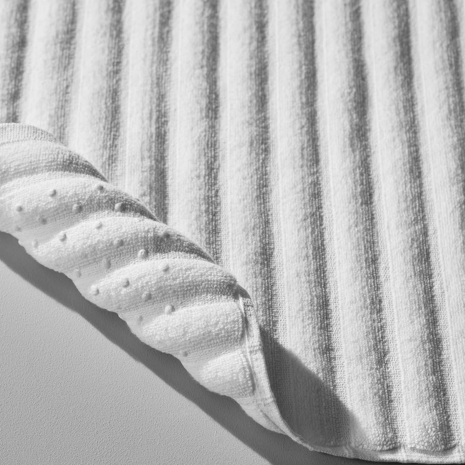 Textured white cotton wave mat with a sculptured edge, perfect for luxurious bathroom rituals.