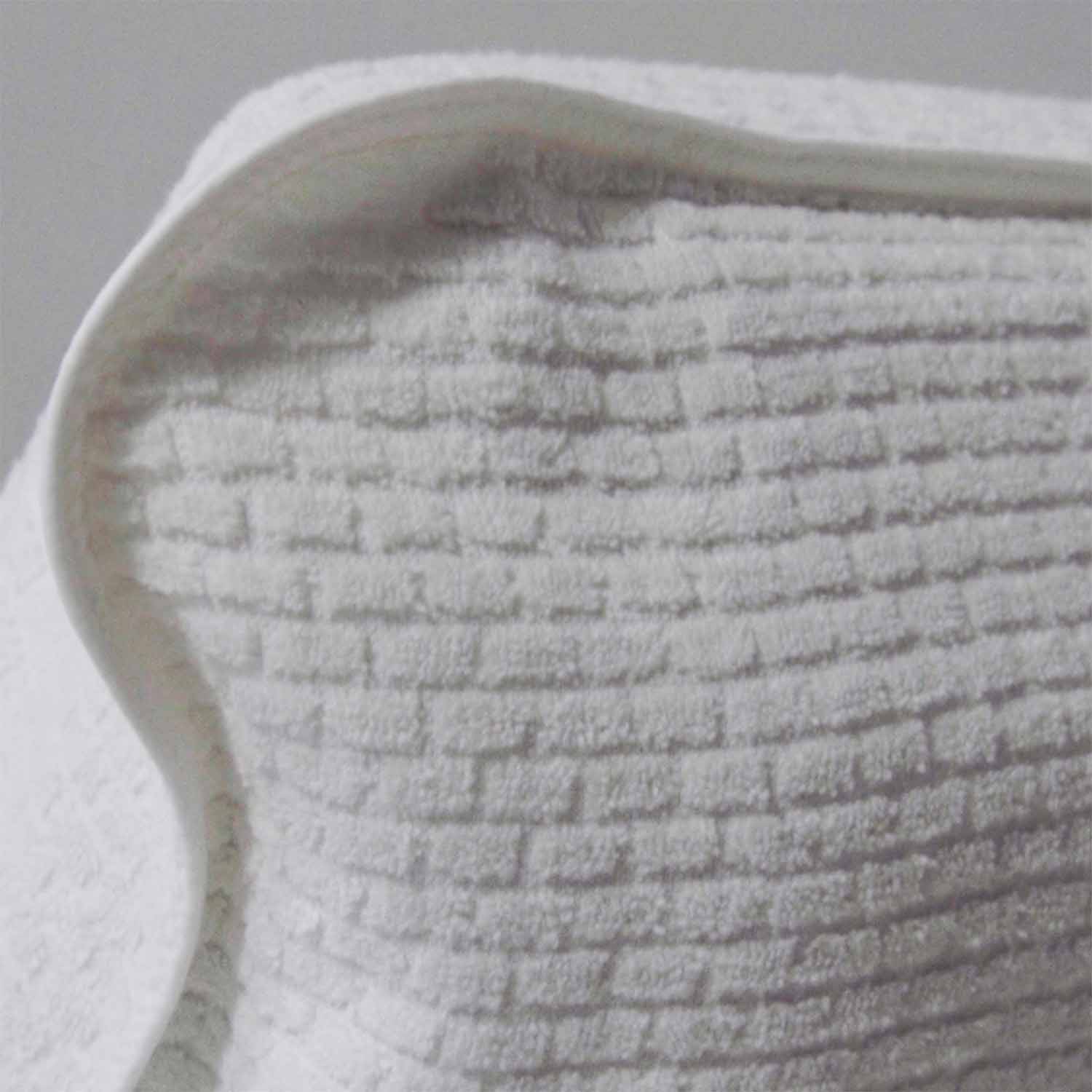 Close-up of textured white cotton towel designed for luxury lounge chair use, soft and stylish for comfort.