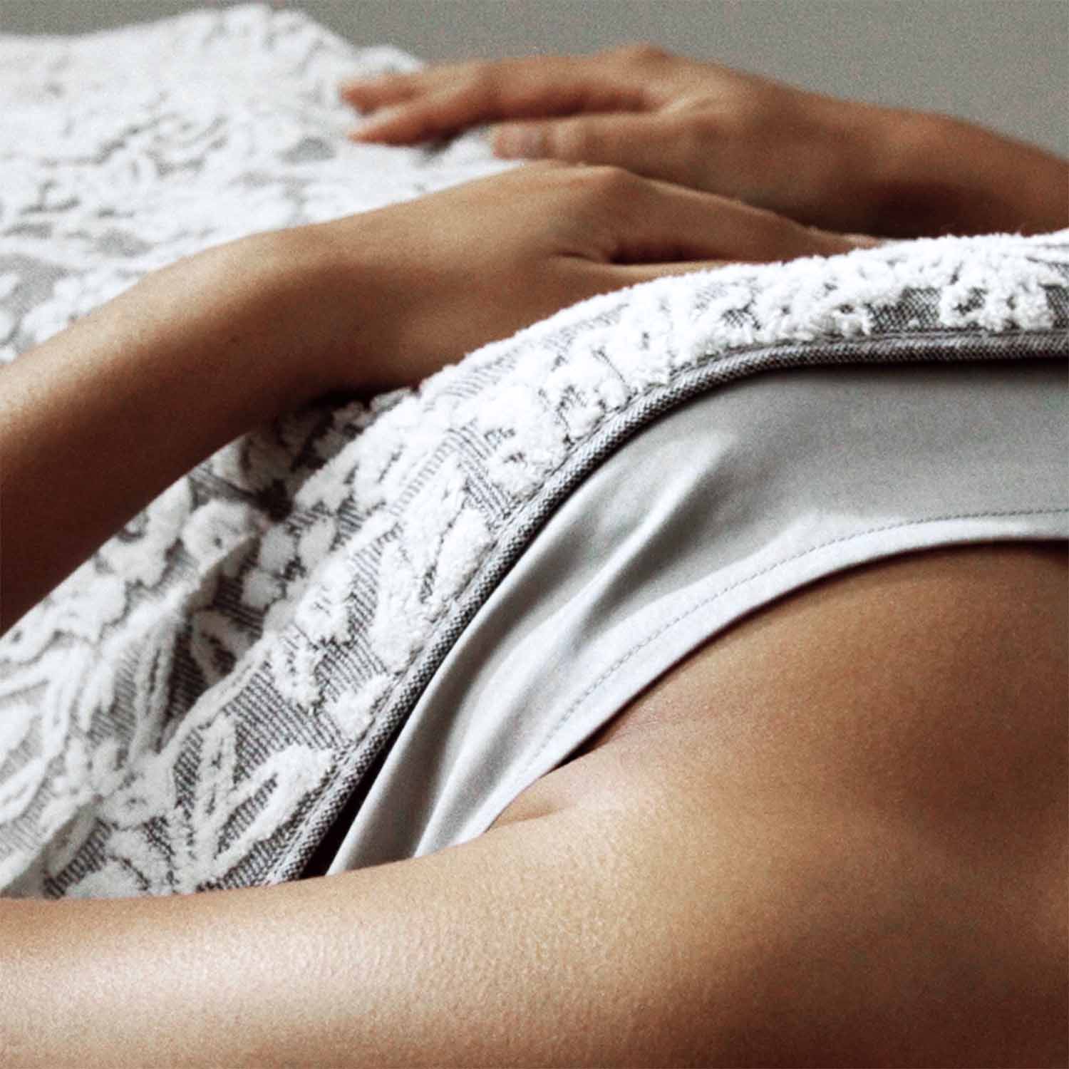 Cozy, two-toned white and grey dyed yarn blanket draped over a person, showcasing its jacquard weave and softness.