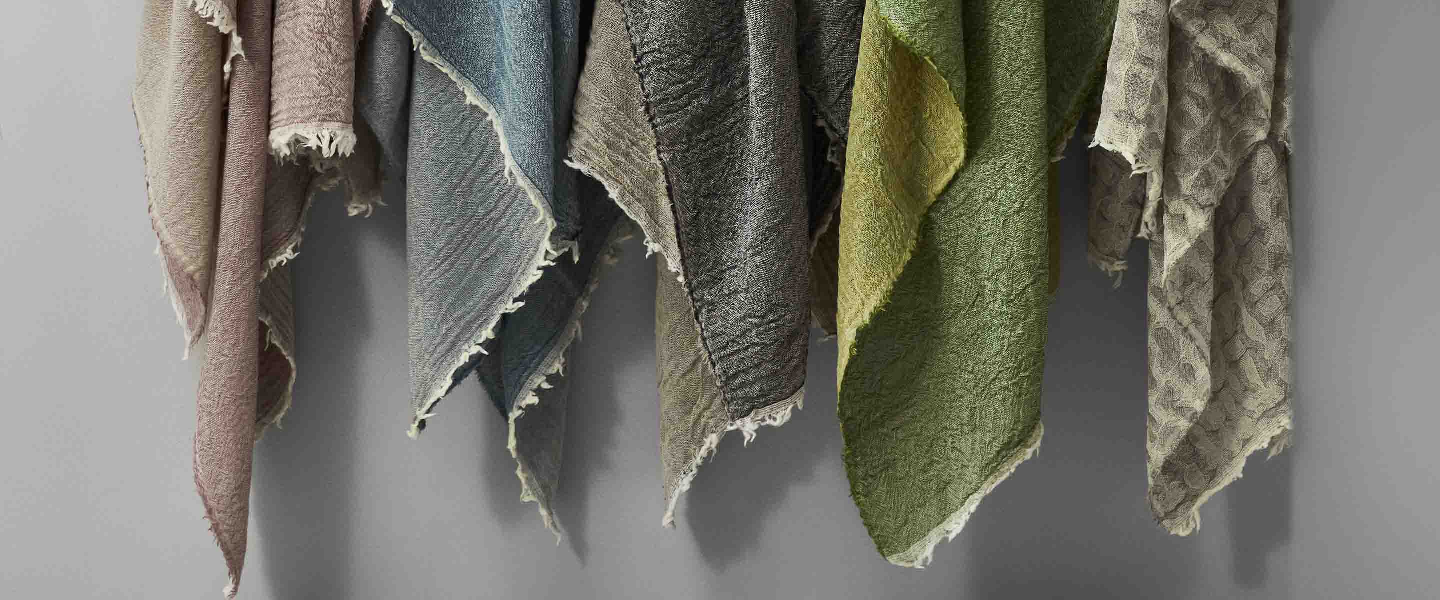 Colorful textiles hanging in an artistic display, showcasing a variety of textures and shades.