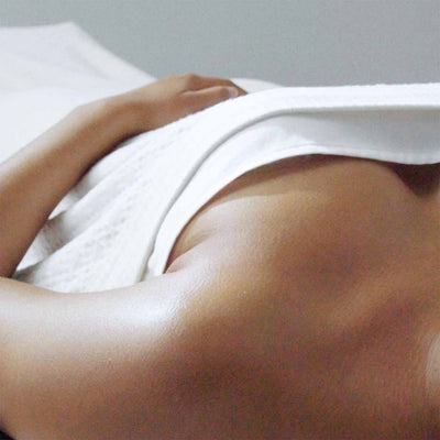 Close-up of a relaxed person lying under a soft cotton blanket, showcasing comfort and luxury in a serene setting.